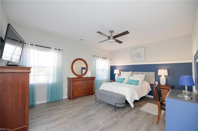 bedroom with ceiling fan, multiple windows, and light hardwood / wood-style flooring