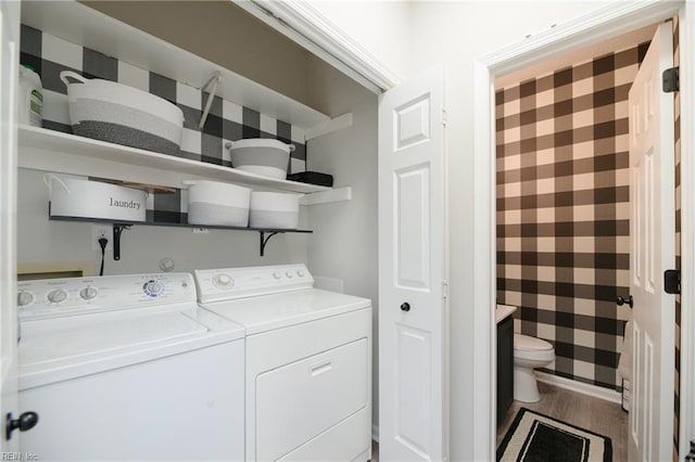 clothes washing area with hardwood / wood-style flooring and washer and dryer