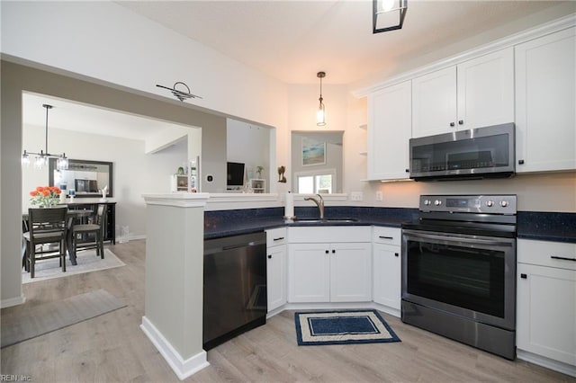 kitchen featuring stainless steel appliances, sink, white cabinets, and decorative light fixtures