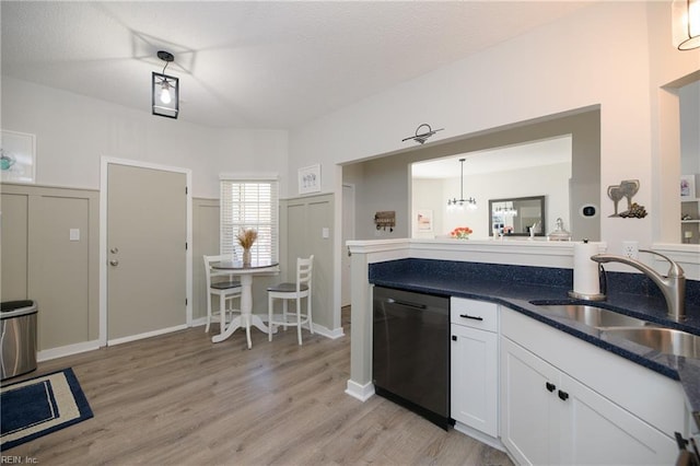 kitchen with sink, light hardwood / wood-style flooring, hanging light fixtures, black dishwasher, and white cabinets