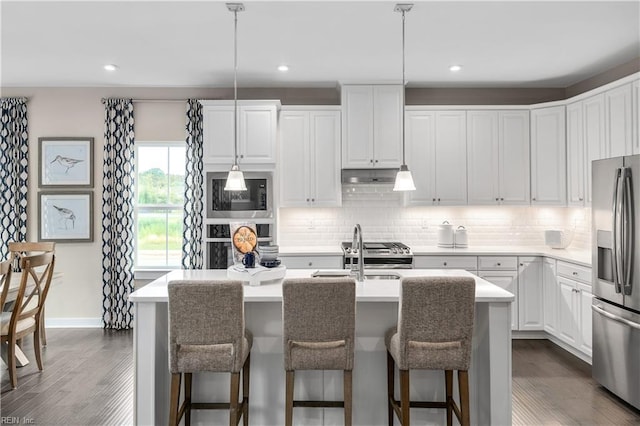 kitchen with stainless steel refrigerator with ice dispenser, an island with sink, hanging light fixtures, and white cabinets