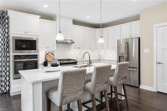 kitchen featuring sink, decorative light fixtures, an island with sink, and appliances with stainless steel finishes