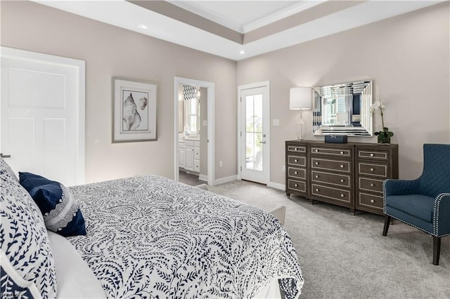 bedroom with a raised ceiling, ornamental molding, light colored carpet, and ensuite bath