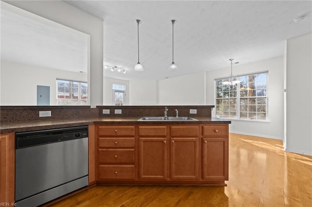 kitchen featuring pendant lighting, sink, a chandelier, stainless steel dishwasher, and light hardwood / wood-style flooring