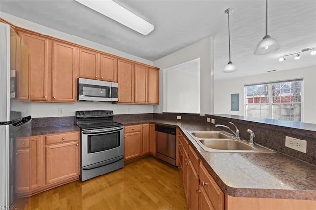 kitchen featuring pendant lighting, sink, light hardwood / wood-style flooring, appliances with stainless steel finishes, and kitchen peninsula