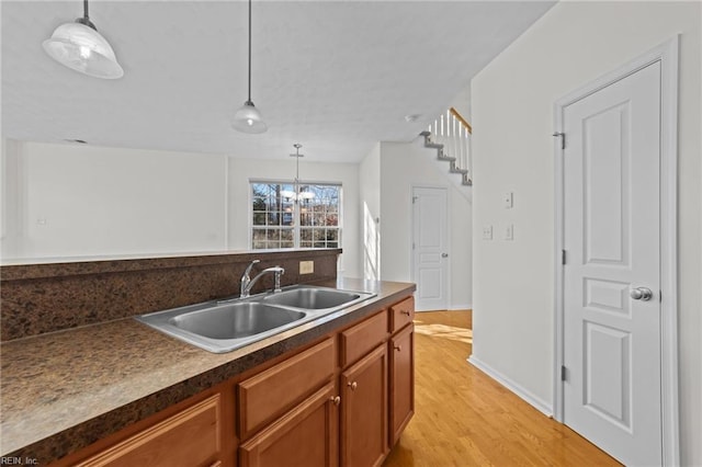 kitchen featuring a chandelier, sink, pendant lighting, and light wood-type flooring