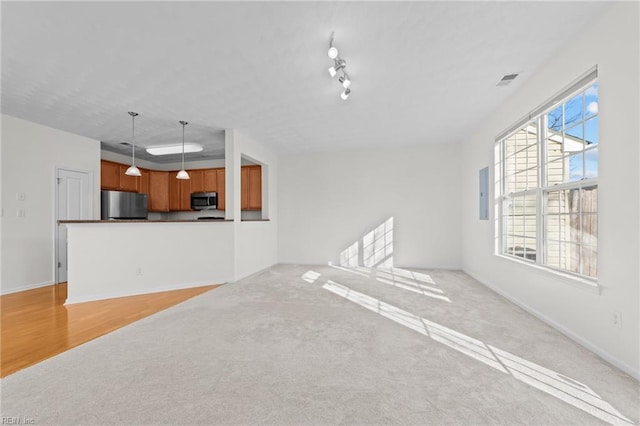 unfurnished living room with track lighting, light colored carpet, and electric panel