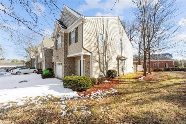 view of snowy exterior with a garage and a yard