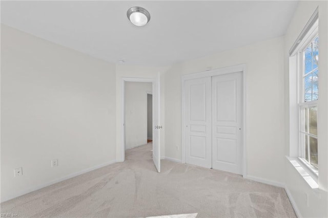 unfurnished bedroom featuring light carpet and a closet