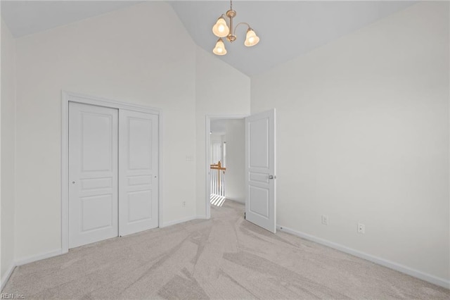 unfurnished bedroom with high vaulted ceiling, light carpet, an inviting chandelier, and a closet