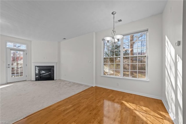 unfurnished living room featuring carpet floors, a wealth of natural light, and a notable chandelier