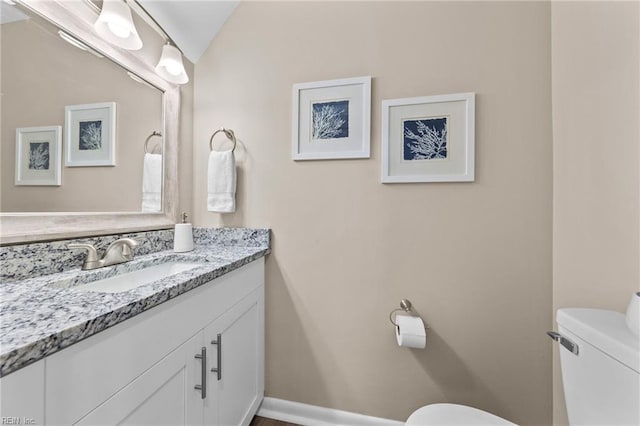 bathroom with vanity, lofted ceiling, and toilet