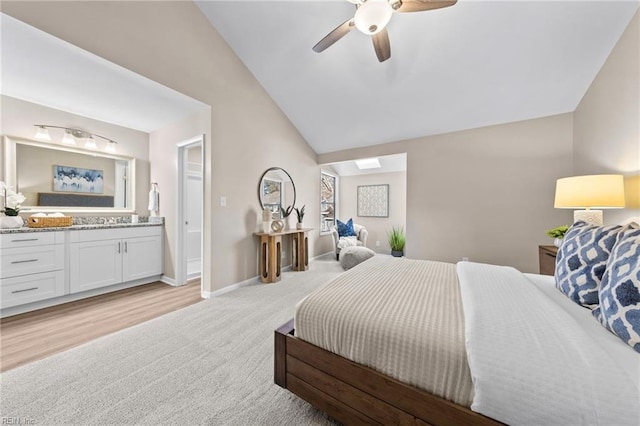 bedroom featuring ensuite bathroom, lofted ceiling, light carpet, and ceiling fan