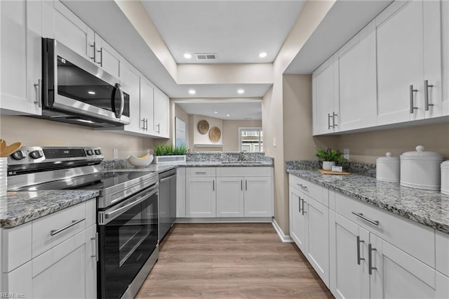 kitchen featuring white cabinetry, light hardwood / wood-style flooring, light stone countertops, and appliances with stainless steel finishes