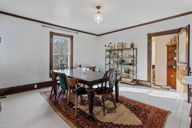 dining room with crown molding and light wood-type flooring