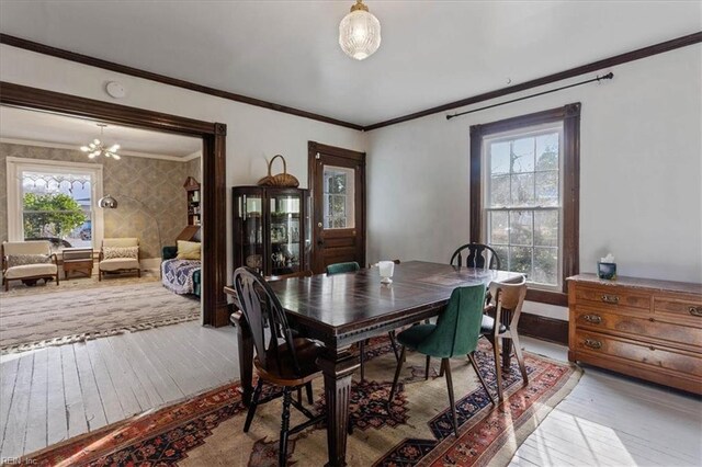 dining area with wood-type flooring, ornamental molding, and plenty of natural light