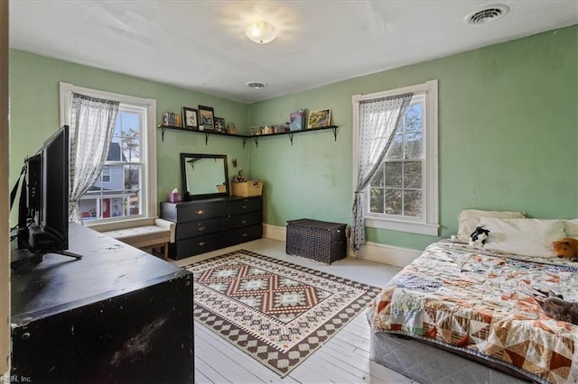 bedroom with multiple windows and light hardwood / wood-style flooring