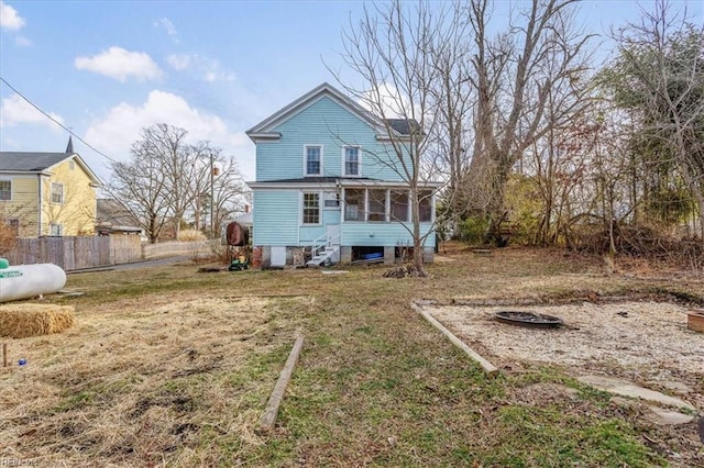 rear view of property featuring a sunroom and a lawn