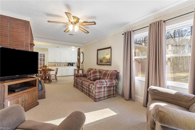 living room with ceiling fan, light colored carpet, and ornamental molding