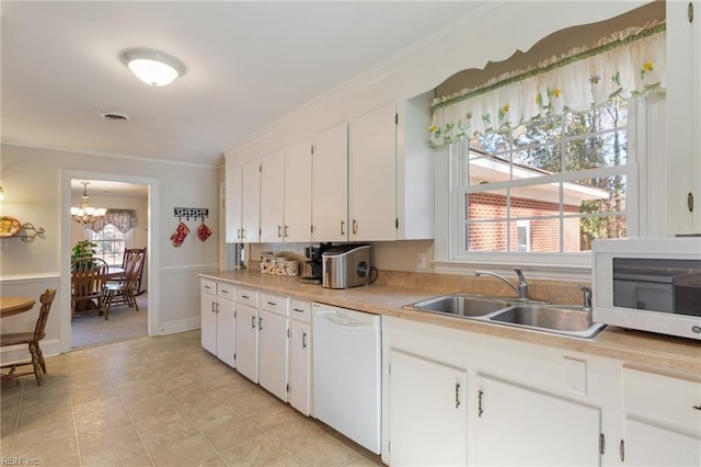 kitchen featuring sink, an inviting chandelier, ornamental molding, white appliances, and white cabinets