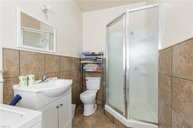 bathroom with vanity, toilet, an enclosed shower, and tile walls