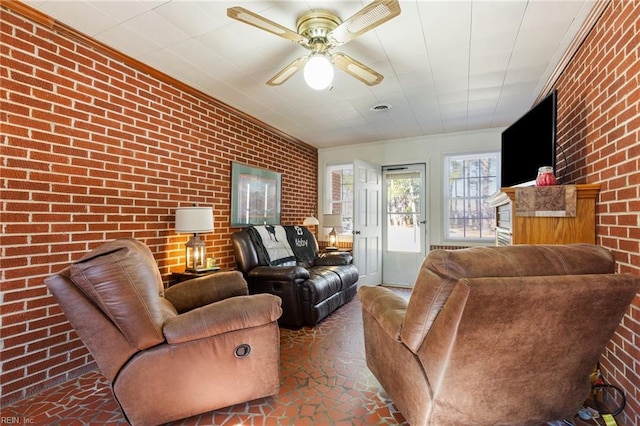 living room featuring ceiling fan, brick wall, and ornamental molding