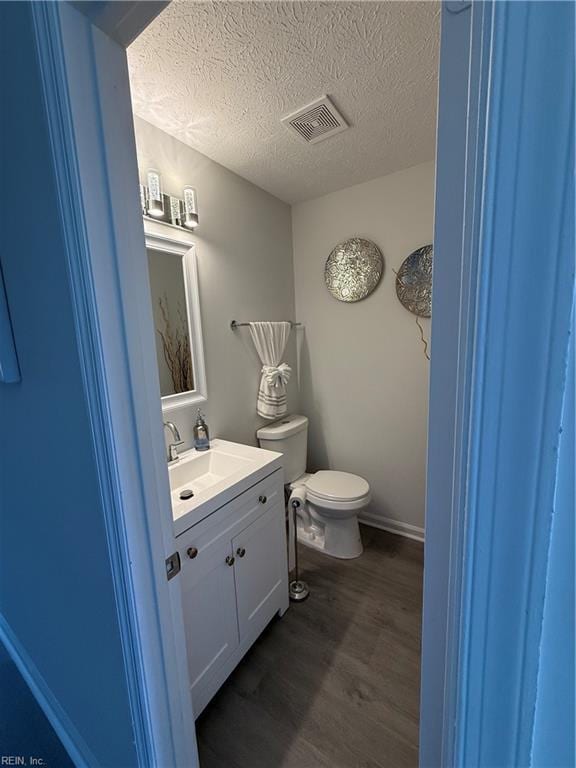 bathroom featuring vanity, a textured ceiling, wood-type flooring, and toilet