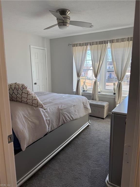 bedroom with ceiling fan, carpet, and a textured ceiling