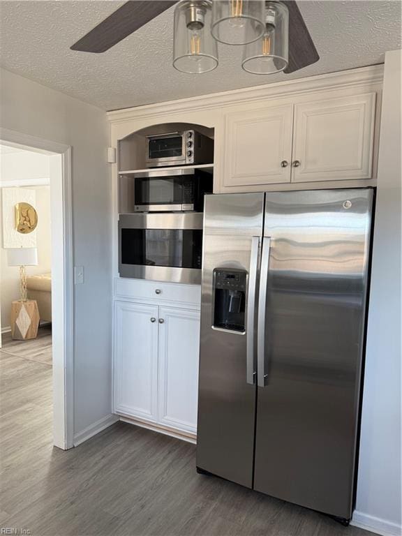 kitchen with a textured ceiling, dark hardwood / wood-style floors, ceiling fan, stainless steel appliances, and white cabinets