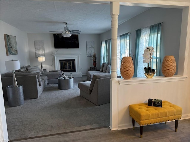 living room with a textured ceiling, ceiling fan, and hardwood / wood-style flooring