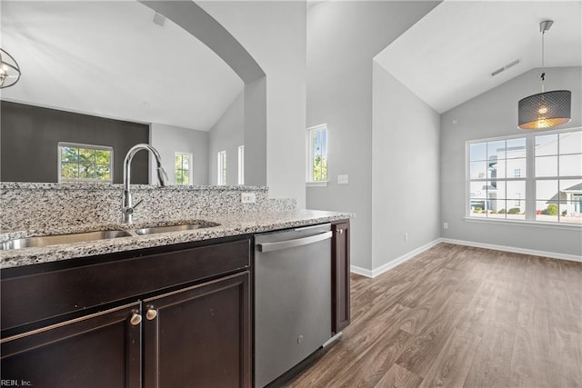 kitchen with vaulted ceiling, dishwasher, light stone countertops, and sink