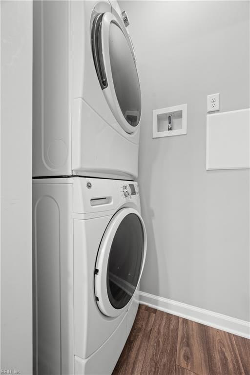 washroom featuring dark wood-type flooring and stacked washer / drying machine