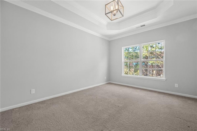 carpeted empty room featuring a raised ceiling, ornamental molding, and a chandelier