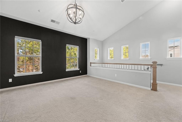 carpeted empty room with a chandelier and high vaulted ceiling