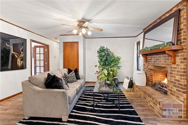 living room featuring hardwood / wood-style flooring, crown molding, a brick fireplace, and ceiling fan