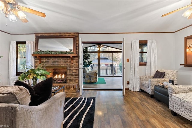 living room with hardwood / wood-style flooring, ceiling fan, a brick fireplace, and a wealth of natural light