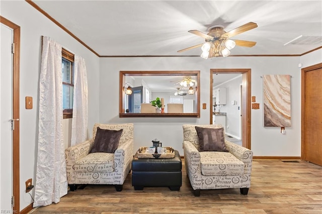 living area with ceiling fan, ornamental molding, and wood-type flooring