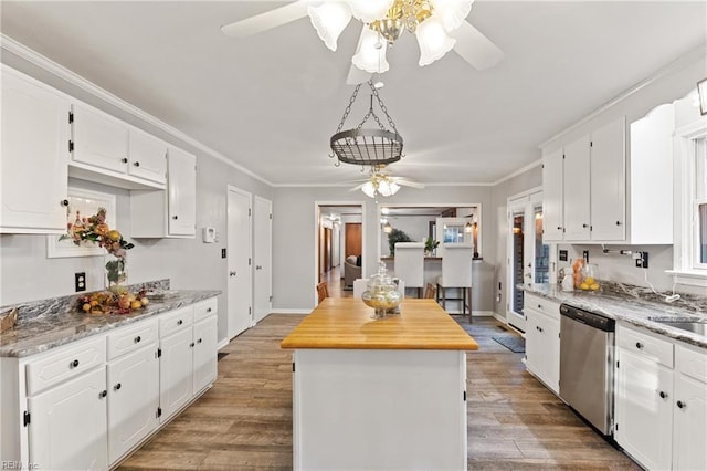 kitchen with light stone counters, dishwasher, a kitchen island, and white cabinets