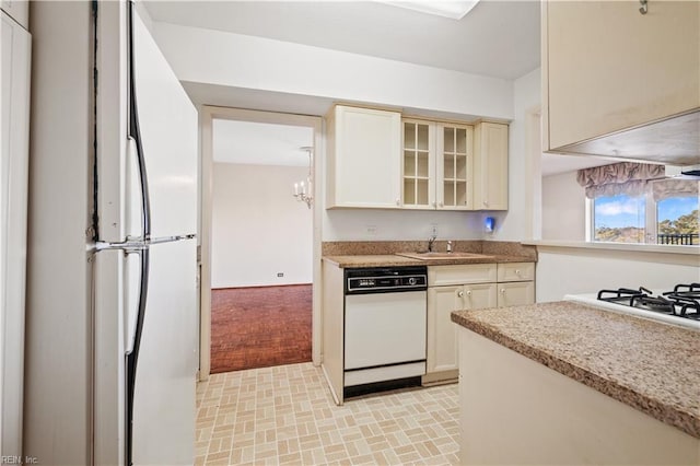 kitchen featuring sink, fridge, white dishwasher, light stone countertops, and cream cabinetry