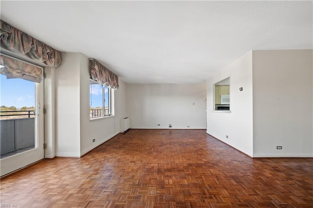 empty room featuring radiator heating unit and dark parquet floors