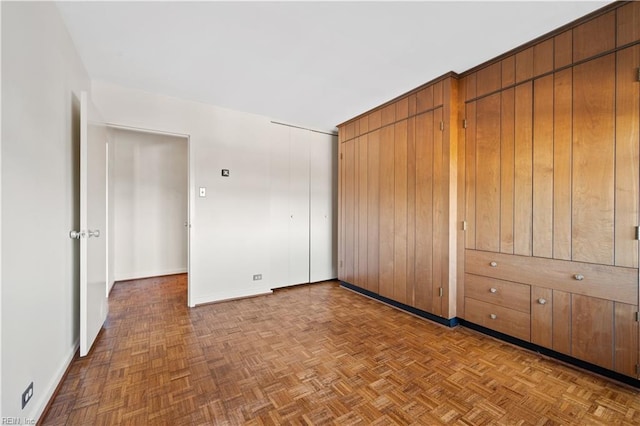 unfurnished bedroom with parquet floors and a closet