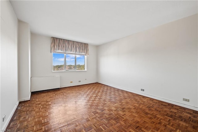 empty room featuring radiator and dark parquet floors