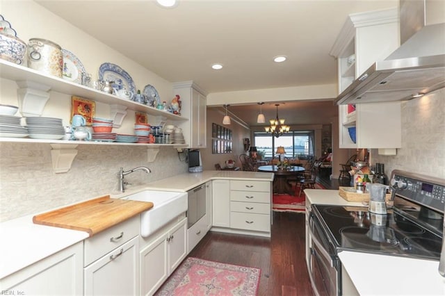 kitchen with sink, decorative light fixtures, electric range, wall chimney range hood, and white cabinets