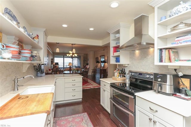 kitchen with pendant lighting, wall chimney range hood, sink, butcher block counters, and double oven range