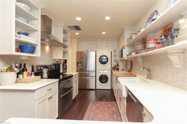 kitchen featuring dark hardwood / wood-style floors, stacked washer / dryer, backsplash, stainless steel appliances, and wall chimney range hood