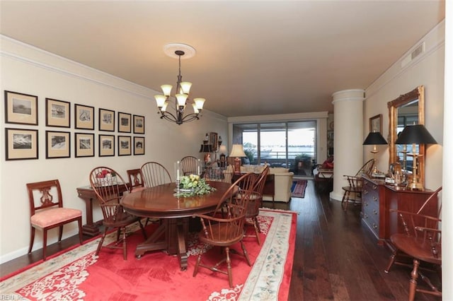 dining room with dark wood-type flooring, ornamental molding, and a chandelier