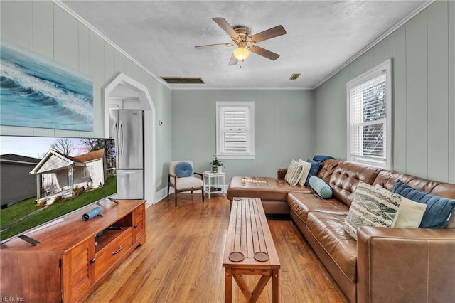 living room featuring ornamental molding, light hardwood / wood-style floors, and ceiling fan