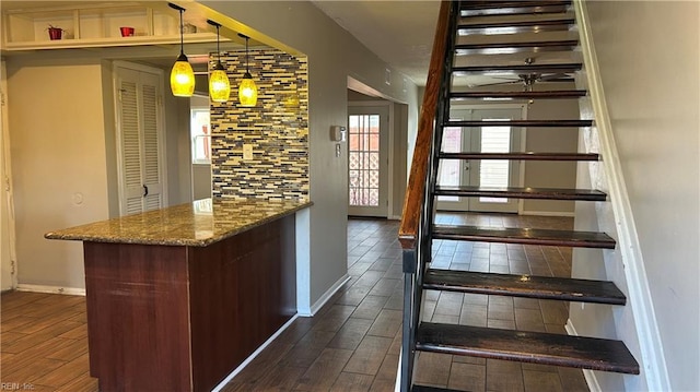 bar with pendant lighting, dark hardwood / wood-style floors, and stone counters