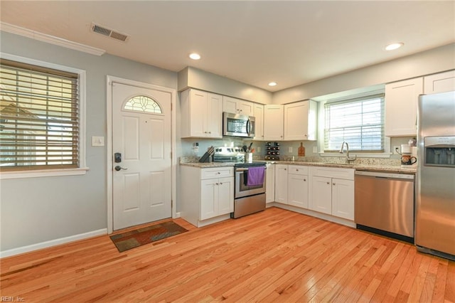 kitchen with white cabinetry, sink, light wood-type flooring, and appliances with stainless steel finishes