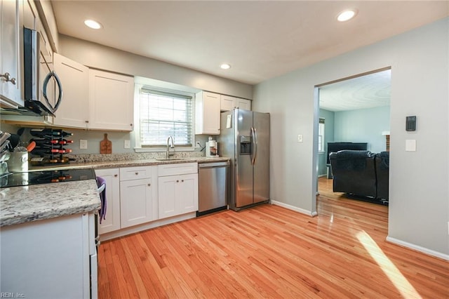 kitchen with light wood-type flooring, appliances with stainless steel finishes, sink, and white cabinets